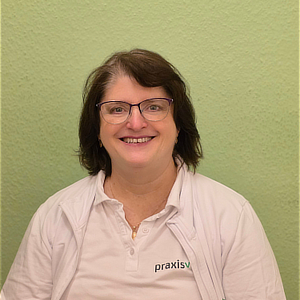 Frau mit braunen Haaren und Brille lacht freundlich vor grünem Hintergrund